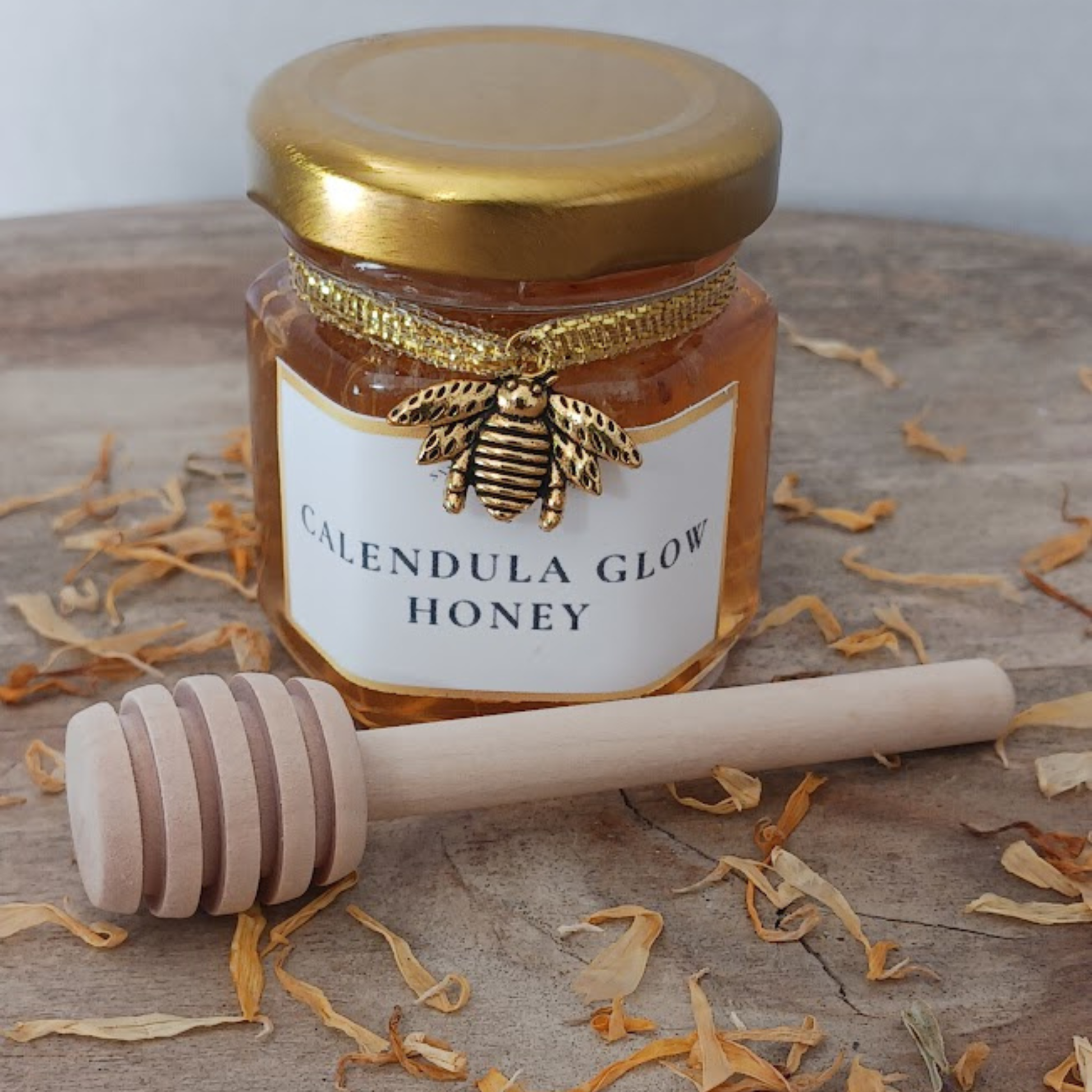 Artisan calendula infused honey on rustic wood with scattered calendula petals and honey dipper